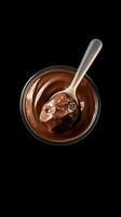 Smooth chocolate dessert in a glass bowl with a spoon on a dark background for indulgent treat lovers photo