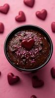 Decadent chocolate dessert surrounded by heart-shaped candies on a pink backdrop for a romantic celebration photo