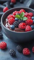 Delicious bowl of dark chocolate topped with fresh berries and mint on a textured background photo