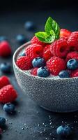 Freshly picked raspberries and blueberries arranged in a decorative bowl with a mint leaf garnish photo