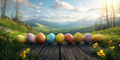 Colorful Easter eggs lined up on wooden surface in a scenic mountain landscape during sunny spring day photo