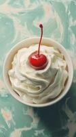 Whipped cream topped dessert with cherry on green marbled surface in bright lighting photo