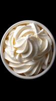 Creamy whipped cream swirls in a white cup on a dark background showcasing dessert preparation and indulgence photo
