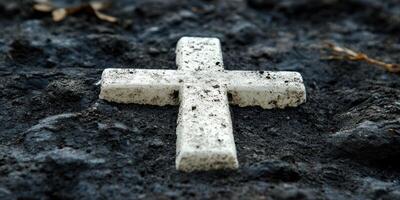 White cross marking a grave in a quiet cemetery surrounded by dark earth and fading vegetation photo