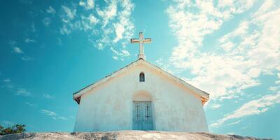 Small white church with cross against a blue sky and clouds on a sunny day in a tranquil setting photo
