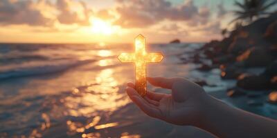 Holding a sparkling cross at sunset by the shoreline while waves gently wash ashore photo