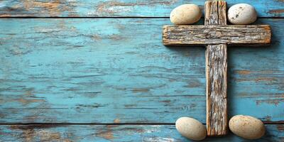 Rustic wooden cross and speckled eggs arranged on a textured blue background for spring celebration photo