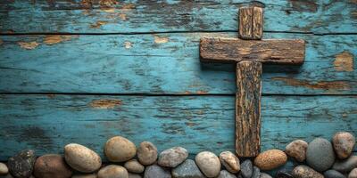 Wooden cross placed on a blue wooden surface surrounded by smooth stones creates a tranquil setting photo