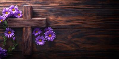 Wooden cross adorned with purple flowers on a rustic wooden surface photo