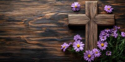 Wooden cross adorned with purple flowers resting on a rustic wooden surface during daylight photo