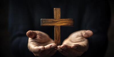 Holding a wooden cross in hands with a dark background conveying a message of faith and spirituality photo