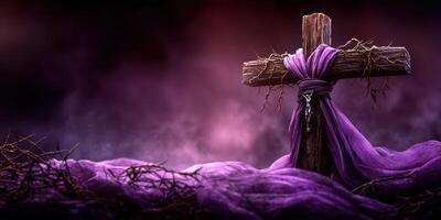 Symbolic wooden cross wrapped in purple cloth surrounded by thorns with a misty background at dusk photo