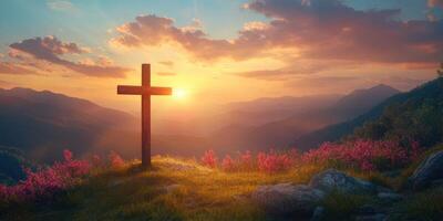 Serene sunset behind a wooden cross on a mountain top with blooming flowers in the foreground photo