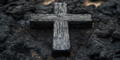 Dark wooden cross rests on textured black surface during twilight, evoking feelings of reflection and reverence photo