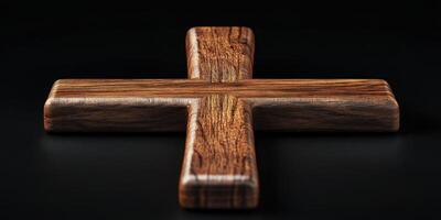 Dark wooden cross placed on a black surface highlighting its intricate grain and craftsmanship photo