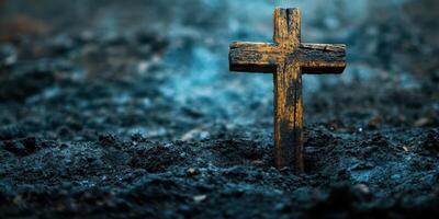 Wooden cross stands alone amidst dark, charred earth in a somber landscape photo