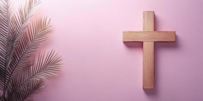 Simple wooden cross displayed against a soft pink background with palm leaves for a serene and peaceful ambiance photo