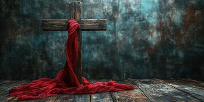 Symbolic wooden cross with a flowing red cloth against a textured backdrop in a calm setting photo