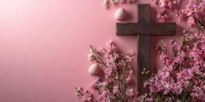 Spring celebration with a wooden cross, colorful eggs, and blooming pink flowers on a soft pink background photo