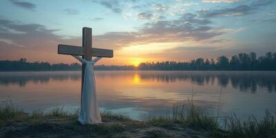 Sunset over tranquil river with wooden cross draped in white cloth symbolizing peace and reflection photo
