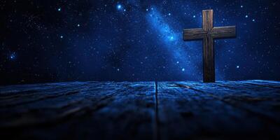 Cross illuminated under a starry night sky with a wooden table surface creating a serene atmosphere for reflection photo