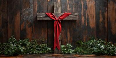 Rustic wooden cross adorned with a red ribbon and greenery on a weathered wooden background photo