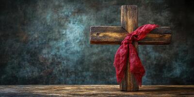 Rustic wooden cross adorned with a red cloth placed against a textured backdrop photo