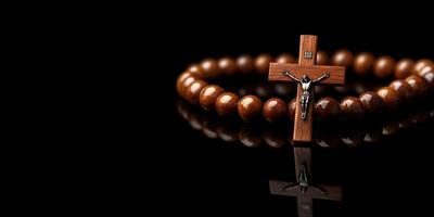Wooden rosary with crucifix displayed on a reflective surface in a darkened setting photo