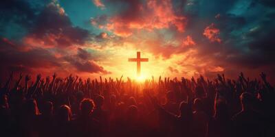 People worshipping at sunset with raised hands towards a cross in a vibrant, colorful sky photo