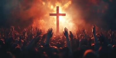Large crowd with raised hands in front of a glowing cross during a nighttime worship event in an outdoor setting photo