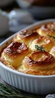 Golden baked puff pastry rolls with herbs in a white dish arranged on a wooden table photo