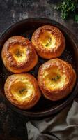 Freshly baked Yorkshire puddings on a rustic wooden table with herbs and dark background photo