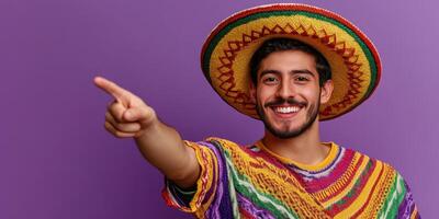 Smiling man in colorful sombrero and traditional attire pointing joyfully against a vibrant purple backdrop photo