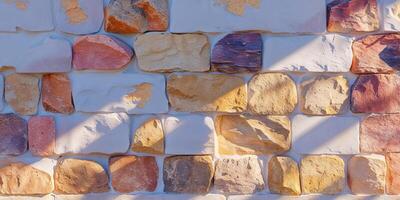 Colorful stone wall texture features various shaped stones and mortar. photo