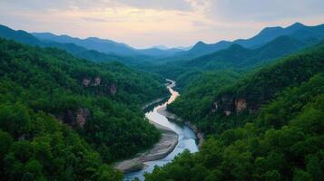 Serene River Winding Through Lush Green Mountain Valley at Sunset photo
