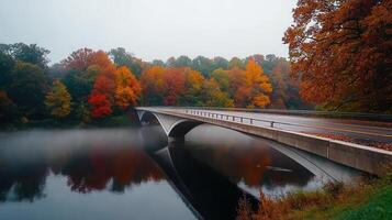 Scenic Autumn Bridge Over Calm River with Vibrant Fall Foliage photo
