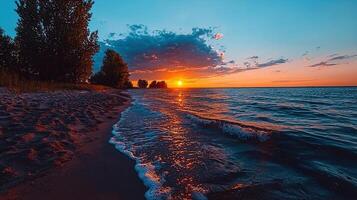 Stunning Sunset over Ocean Beach with Sandy Shore and Silhouetted Trees photo