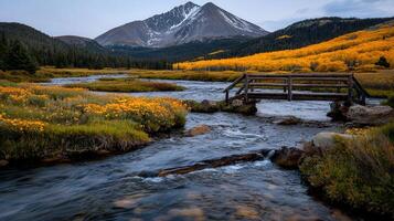 Serene Autumn Creek with Wooden Bridge Mountain and Golden Aspen Trees photo