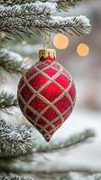 Red christmas ornament with gold accents hanging on a snowy evergreen tree photo