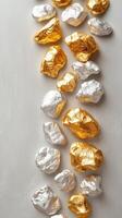 Gold and silver foil rocks arranged in a stylish pattern on a neutral background photo