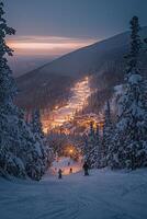 Skiers in a snowy mountain landscape at dusk with illuminated resort below photo