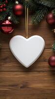 Blank white heart ornament surrounded by christmas decorations on wooden table photo