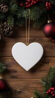 Blank white heart ornament surrounded by christmas decorations and pine cones photo