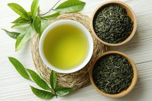 Fresh green tea in bowl surrounded by tea leaves and dried green tea leaves photo