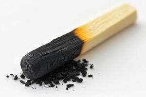 Close-up of a burned matchstick with black charred residue on a white background photo