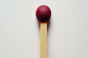 Close-up of a matchstick with a red tip isolated on a light background photo