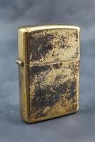Vintage brass zippo lighter with patina and textured surface photo
