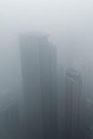 Tall skyscrapers shrouded in thick fog creating a mysterious urban atmosphere photo