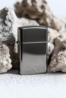 Silver metal zippo lighter surrounded by textured gray rocks photo