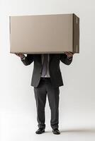 Businessman in suit holding large cardboard box above his head in studio setting photo